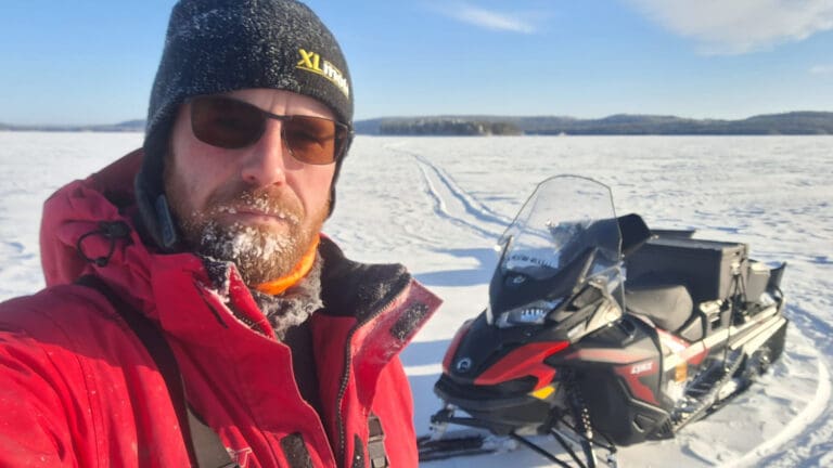 PIKES-uutiset: kuvassa ammattikalastaja Tomi Tuovinen moottorikelkkoineen Pielisellä.